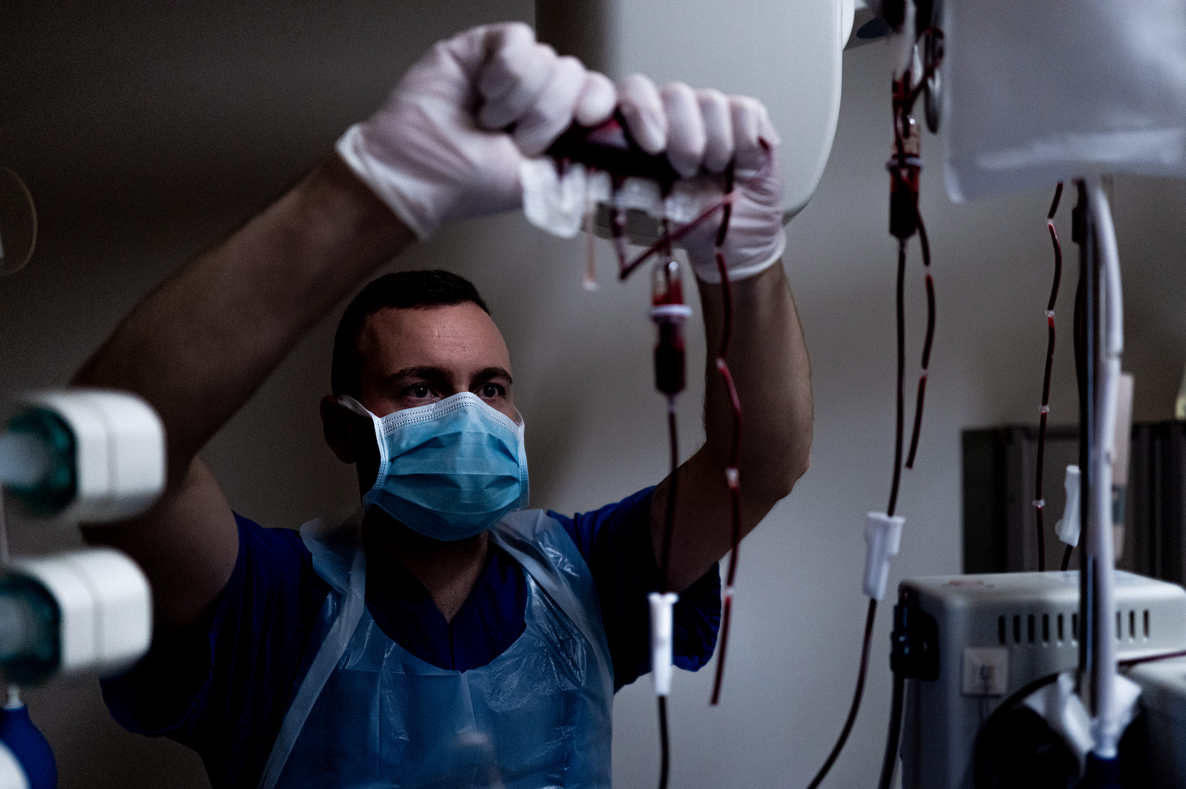 Der Intensivpfleger Lars drückt während einer Operation die letzten Reste einer Blutkonserve in einen Patienten. 